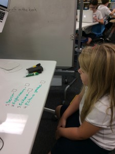 A 4th grader working through her checklist/rubric on a whiteboard table